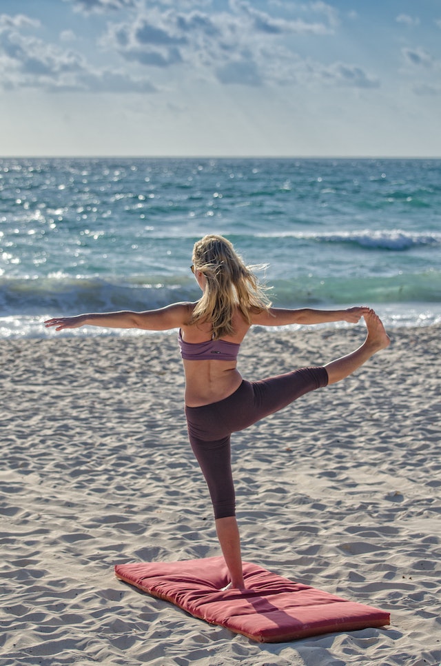 dame doet yogo op strand